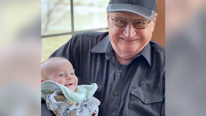 An elder man holding a newborn baby