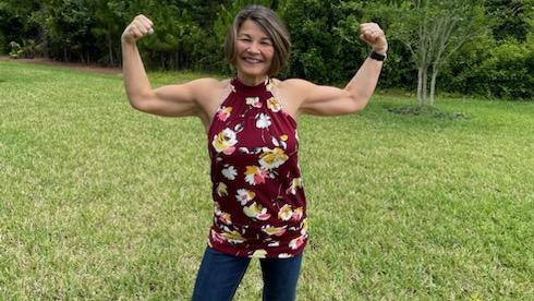 A lady standing on grass showing her muscles